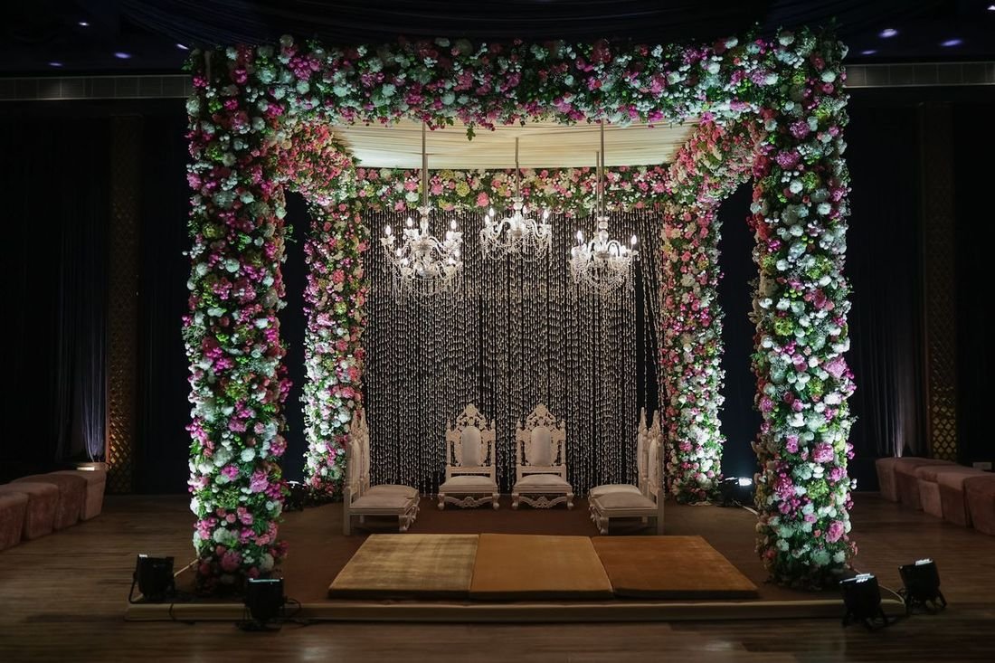 Indoor mandap decorated with flowers and chandeliers