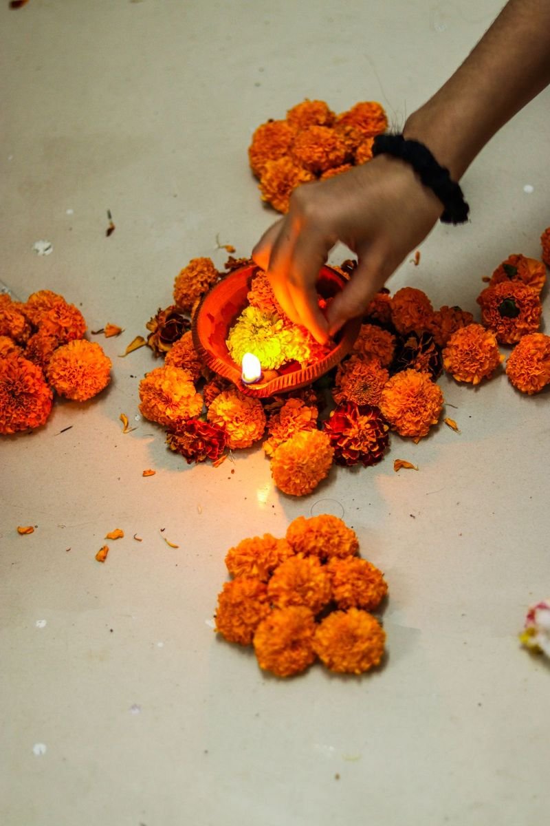 Hand lighting a diya among marigold flowers