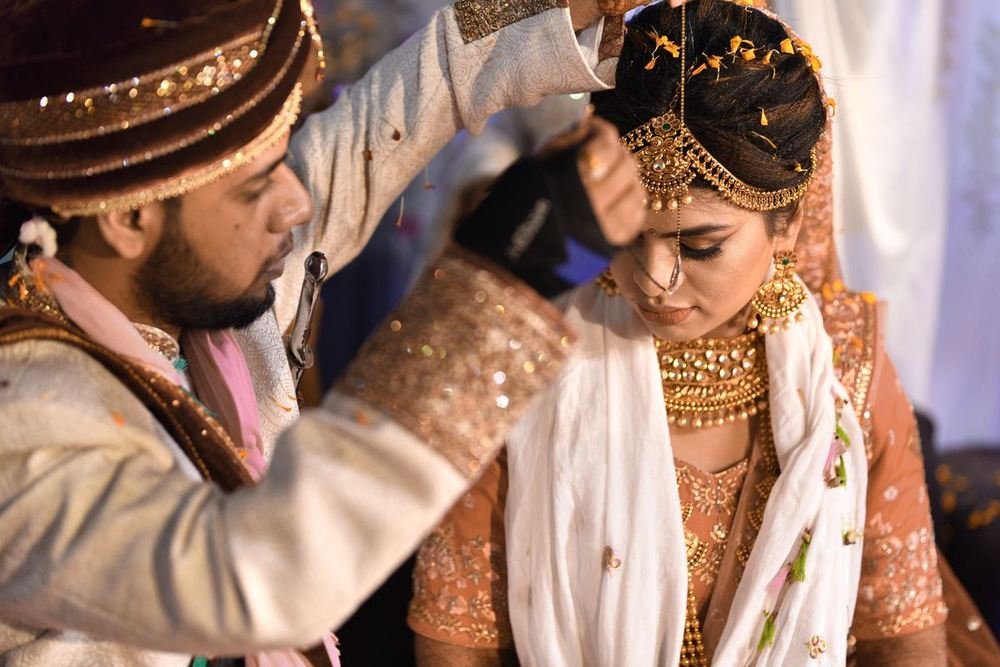 Groom tying the bride's jewellery at the wedding