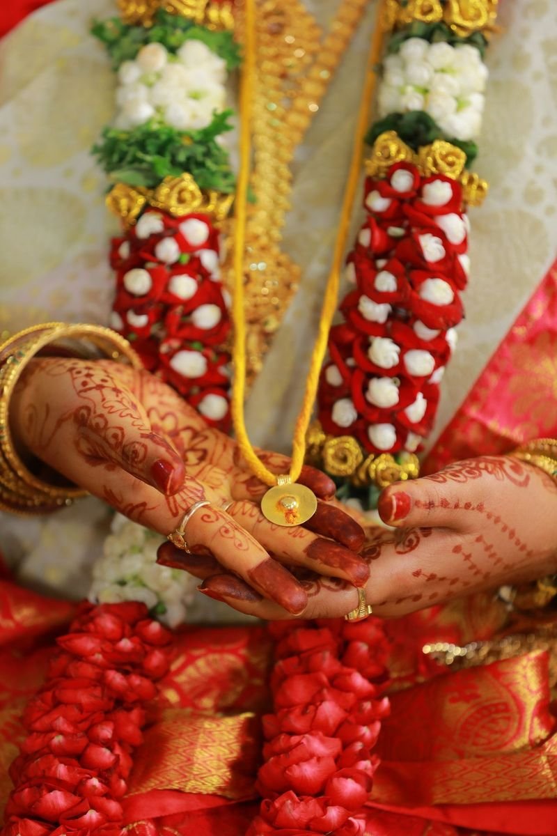 Bride's hennaed hands holding a flower varmala